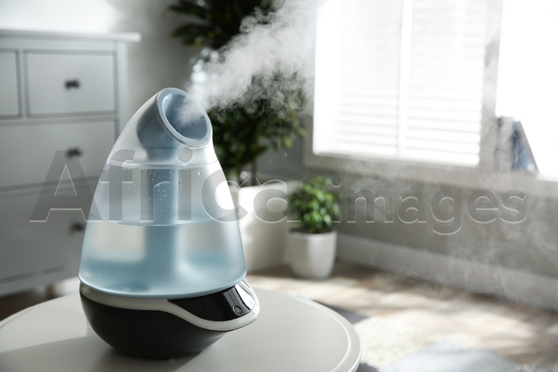 Modern air humidifier on table indoors. Space for text