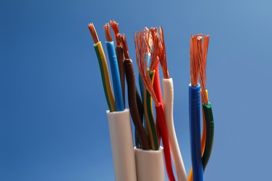 Many stripped electrical cables on blue background, closeup