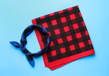 Tied and folded checkered bandanas on light blue background, flat lay