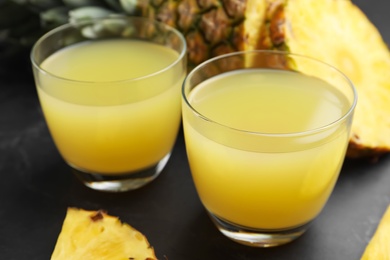 Photo of Delicious fresh pineapple juice on black table, closeup