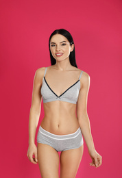 Beautiful young woman in grey sportive underwear on pink background