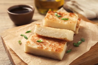 Delicious turnip cake with green onion on wooden board, closeup
