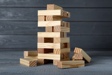 Jenga tower and wooden blocks on grey table. Board game