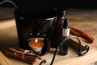 Aroma lamp and cinnamon essential oil on wooden tray