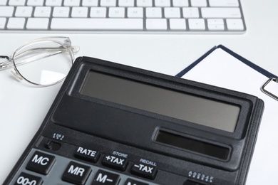 Calculator, clipboard, keyboard and glasses on white background, closeup. Tax accounting