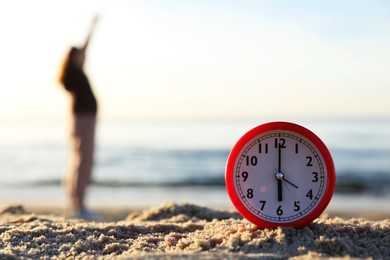 Photo of Woman doing morning exercises near river outdoors, focus on alarm clock