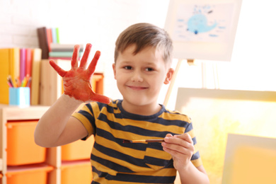 Cute little child with painted palm in room