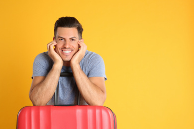 Handsome man with suitcase for summer trip on yellow background. Vacation travel