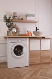Laundry room interior with modern washing machine and stylish vessel sink on countertop