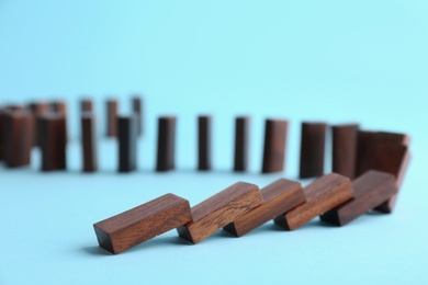 Falling wooden domino tiles on light blue background