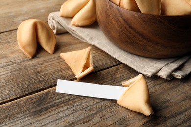Tasty fortune cookies and paper with prediction on wooden table. Space for text