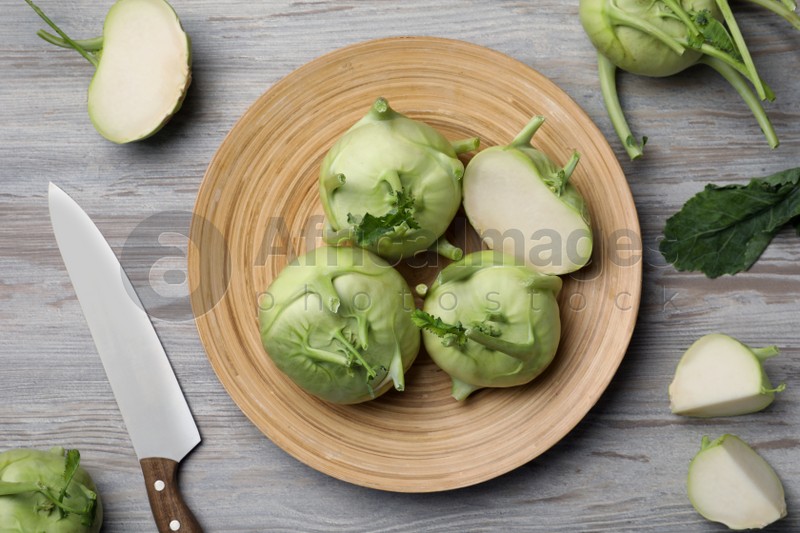 Whole and cut kohlrabi plants on wooden table, flat lay