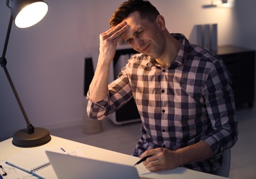 Photo of Overworked man with headache in office