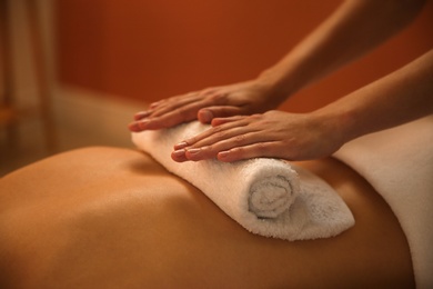 Photo of Young woman receiving hot towel massage in spa salon, closeup