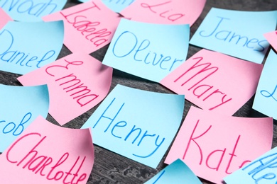 Photo of Paper notes with different baby names on grey background