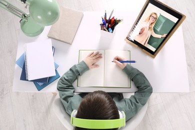 Cute little boy with modern tablet at online lesson, top view. E-learning