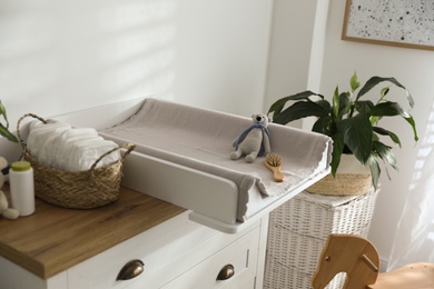 Chest of drawers with changing pad and tray in nursery. Baby room interior design