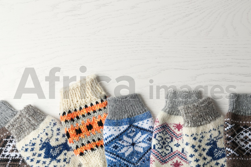 Soft knitted socks on white wooden background, flat lay with space for text. Winter clothes
