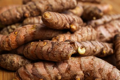 Photo of Many whole turmeric roots on wooden table, closeup