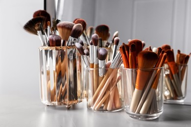 Photo of Set of professional makeup brushes near mirror on grey table
