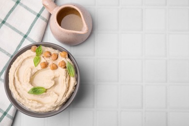 Delicious hummus with chickpeas served on white tiled table, flat lay. Space for text