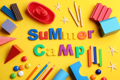 Flat lay composition with phrase SUMMER CAMP made of magnet letters on yellow background
