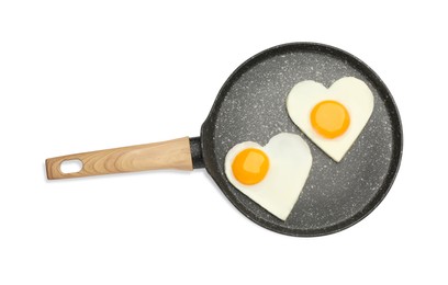 Heart shaped fried eggs in frying pan isolated on white, top view