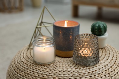 Photo of Lit candles and decor elements on wicker pouf indoors