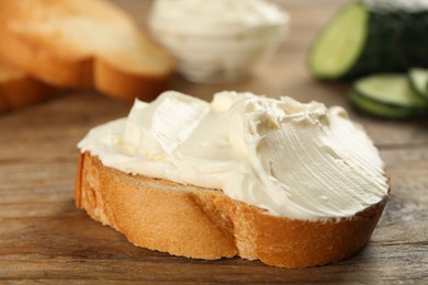 Photo of Delicious sandwich with cream cheese on wooden table, closeup