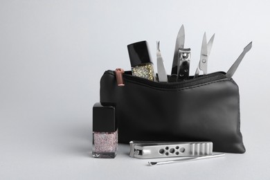 Photo of Set of manicure tools in bag on grey background