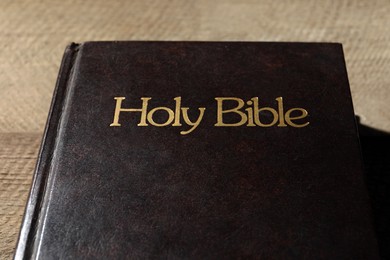 Photo of One hardcover Bible on wooden table, closeup