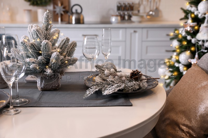 Table with set of dishware and beautiful Christmas decor in kitchen. Interior design