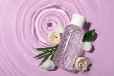 Photo of Flat lay composition with wet bottle of micellar water on violet background. Space for text