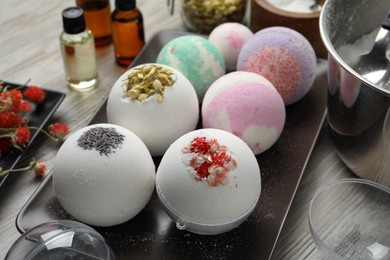 Plate with different bath bombs on wooden table, closeup