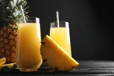 Photo of Delicious pineapple juice and fresh fruit on black wooden table, closeup