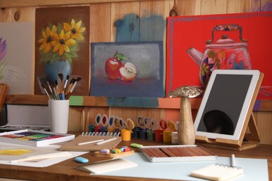 Artist's workplace with tablet, drawings, soft pastels and color pencils on table