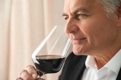 Senior man with glass of wine indoors