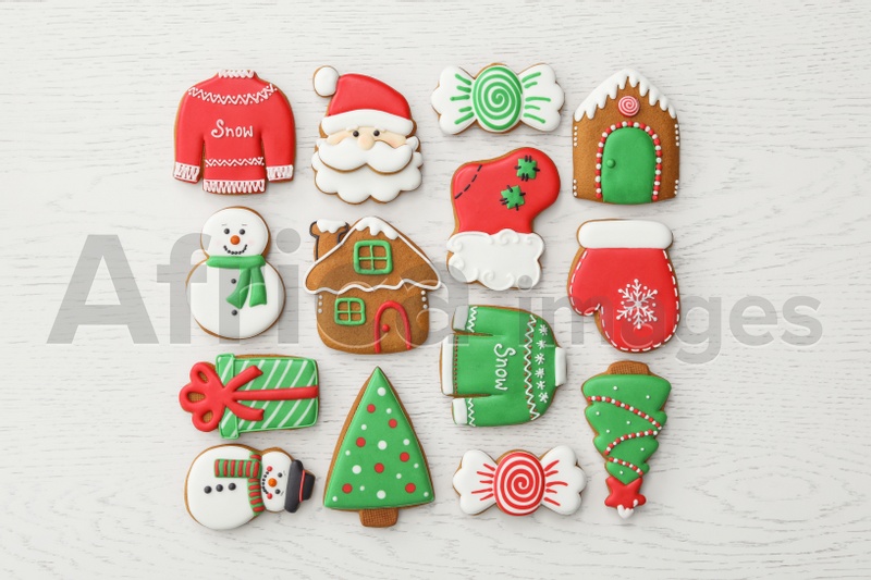 Different Christmas gingerbread cookies on white wooden table, flat lay