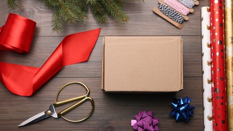 Box, wrapping paper and scissors on wooden table, flat lay
