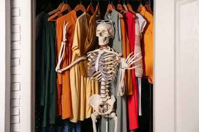 Artificial human skeleton model among clothes in wardrobe