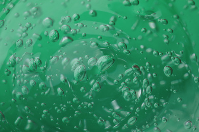 Pure transparent cosmetic gel on green background, closeup