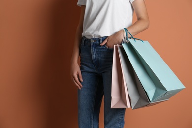 Woman with paper shopping bags on light brown background, closeup