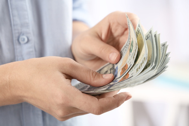 Photo of Woman counting money on blurred background, closeup