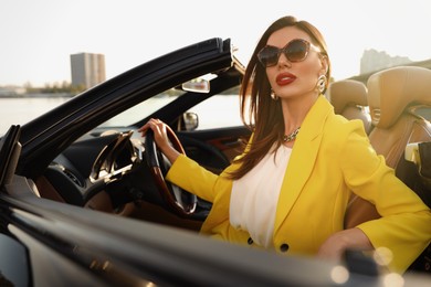 Beautiful businesswoman in luxury convertible car outdoors
