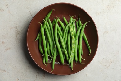 Fresh green beans in bowl on light grey table, top view