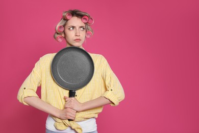 Photo of Young housewife with frying pan on pink background. Space for text