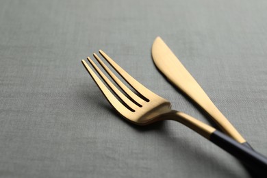 Photo of Golden fork and knife on grey table, closeup