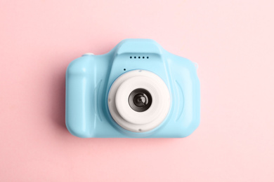 Light blue toy camera on pink background, top view. Future photographer