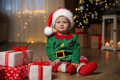 Baby in cute Christmas outfit with gifts at home