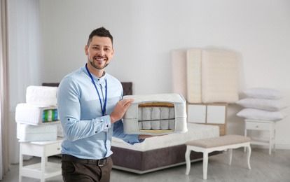 Salesman with section of mattress in furniture store